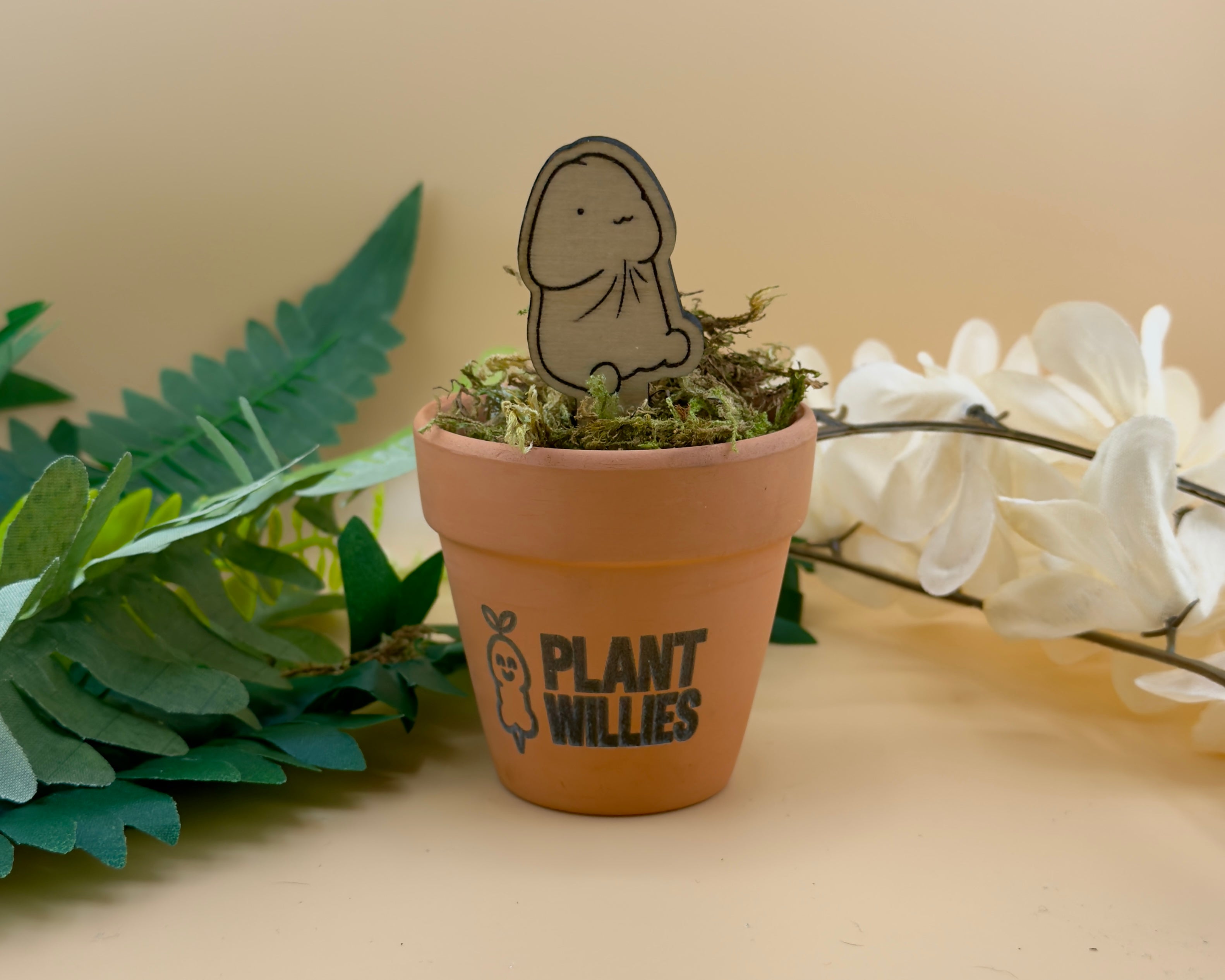 Chubby Bud wooden plant stake with relaxed expression sitting in a terracotta pot.